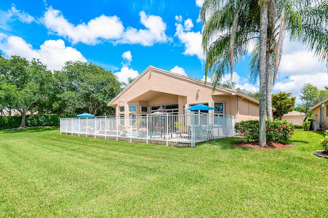 rear view of house with a fenced in pool and a yard