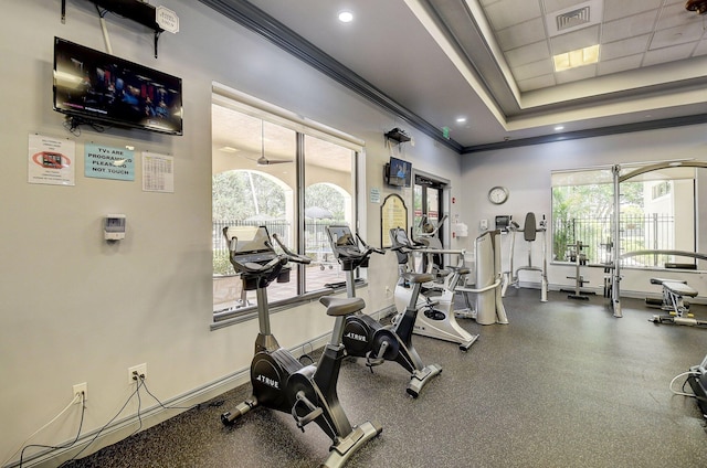 exercise room with ornamental molding, healthy amount of natural light, baseboards, recessed lighting, and a tray ceiling