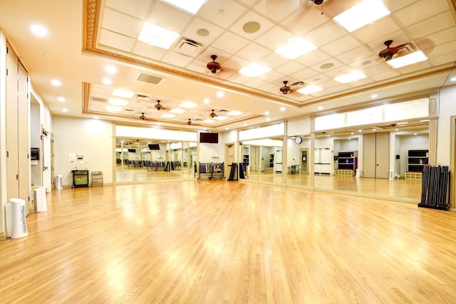 exercise room featuring light hardwood / wood-style floors and a tray ceiling