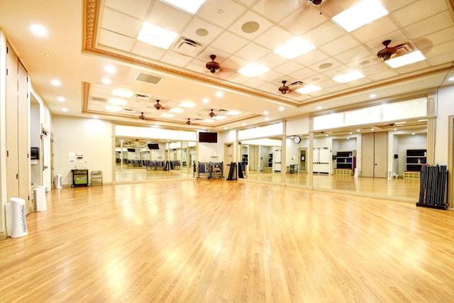 workout room featuring wood finished floors, a paneled ceiling, a raised ceiling, and ceiling fan