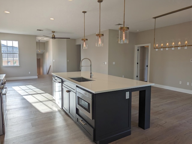 kitchen featuring appliances with stainless steel finishes, light hardwood / wood-style flooring, sink, and a center island with sink