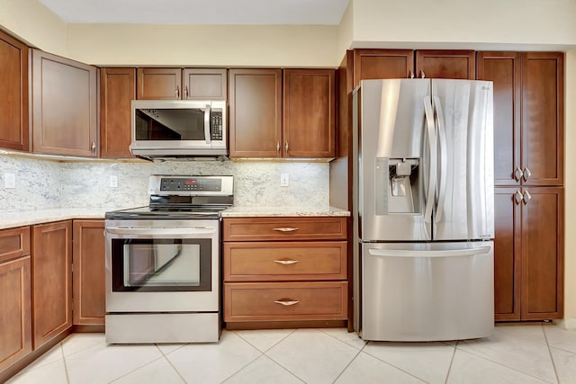 kitchen with decorative backsplash, light stone countertops, stainless steel appliances, and light tile patterned floors