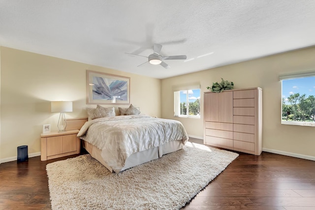 bedroom with ceiling fan, a textured ceiling, and dark hardwood / wood-style floors