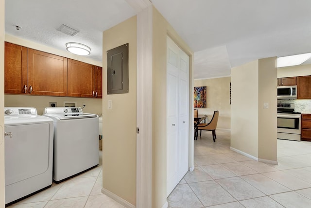 washroom featuring independent washer and dryer, light tile patterned flooring, cabinets, and electric panel