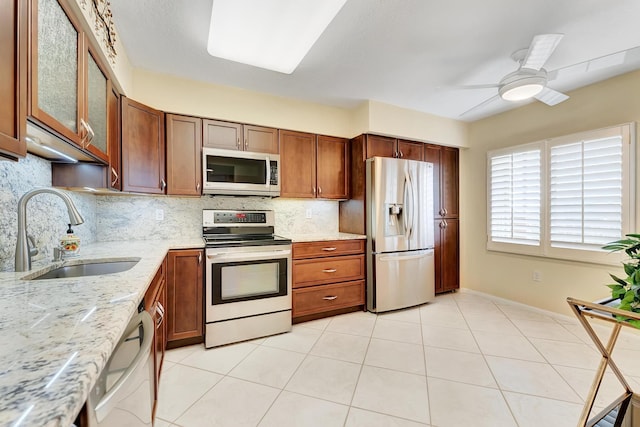 kitchen featuring decorative backsplash, sink, appliances with stainless steel finishes, light stone counters, and ceiling fan