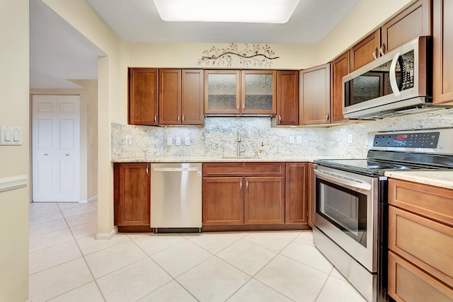 kitchen with sink, backsplash, appliances with stainless steel finishes, and light tile patterned flooring