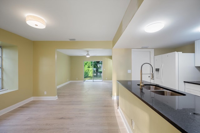 kitchen featuring dark stone countertops, light hardwood / wood-style floors, sink, and white cabinets