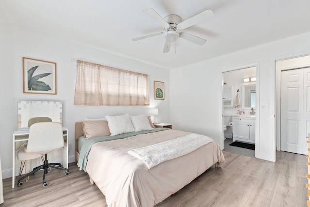 bedroom featuring light wood-type flooring, ensuite bathroom, ceiling fan, and sink