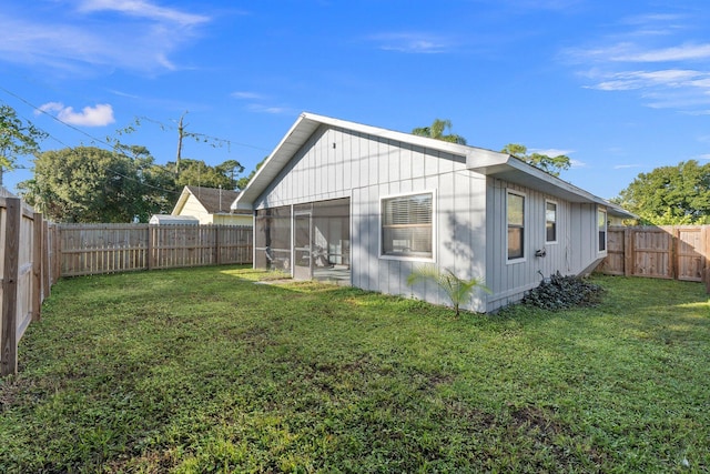 rear view of house featuring a sunroom and a lawn