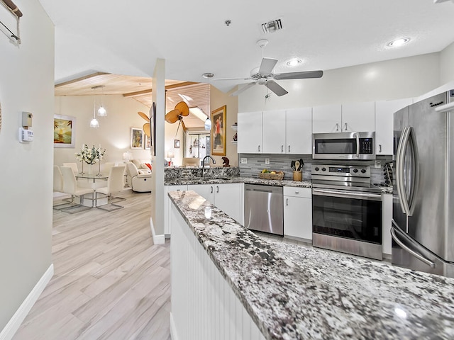 kitchen featuring light stone countertops, vaulted ceiling with beams, ceiling fan, stainless steel appliances, and white cabinets