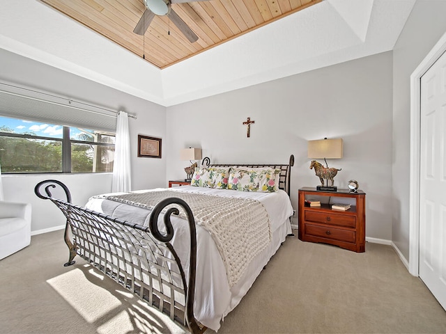 bedroom featuring a tray ceiling, light colored carpet, wooden ceiling, and ceiling fan