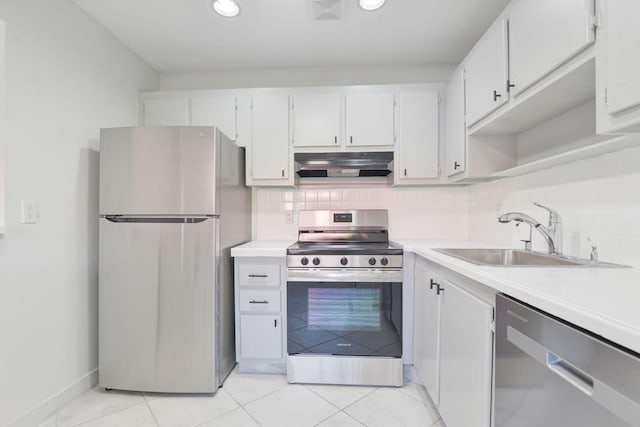 kitchen with appliances with stainless steel finishes, sink, backsplash, white cabinetry, and light tile patterned floors