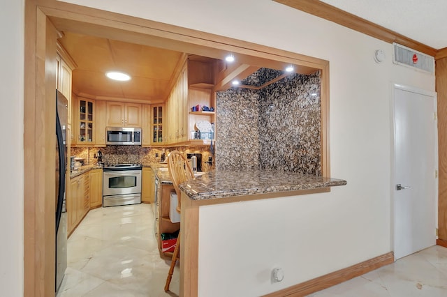 kitchen featuring kitchen peninsula, tasteful backsplash, dark stone countertops, crown molding, and stainless steel appliances