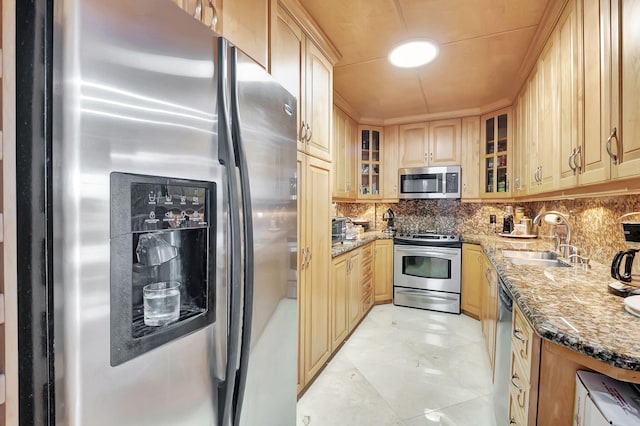 kitchen featuring appliances with stainless steel finishes, sink, dark stone counters, and light brown cabinets