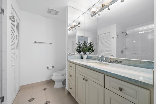 bathroom featuring tiled shower, tile patterned flooring, vanity, and toilet