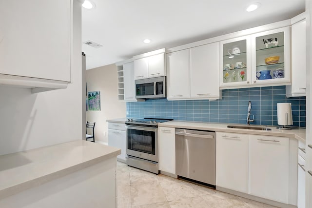 kitchen with backsplash, white cabinetry, sink, and stainless steel appliances