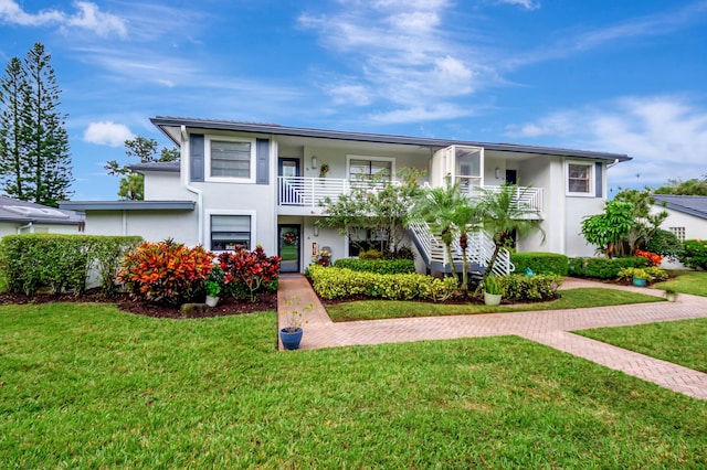 view of front of property featuring a balcony and a front lawn