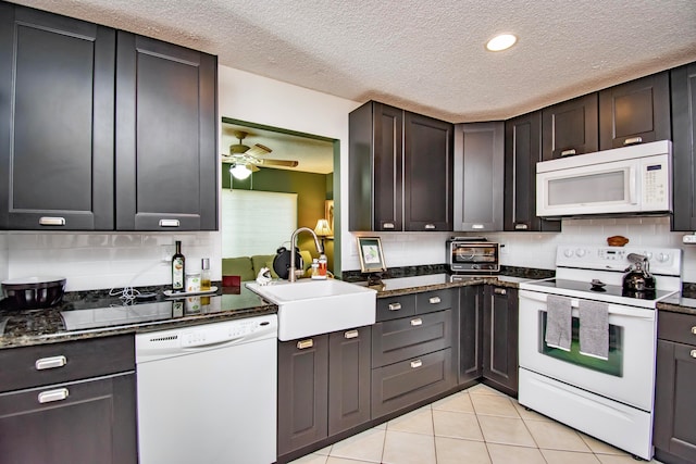 kitchen with white appliances, tasteful backsplash, sink, and dark stone countertops