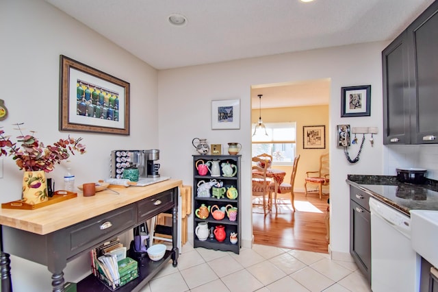 kitchen featuring light tile patterned floors, wood counters, dishwasher, and pendant lighting