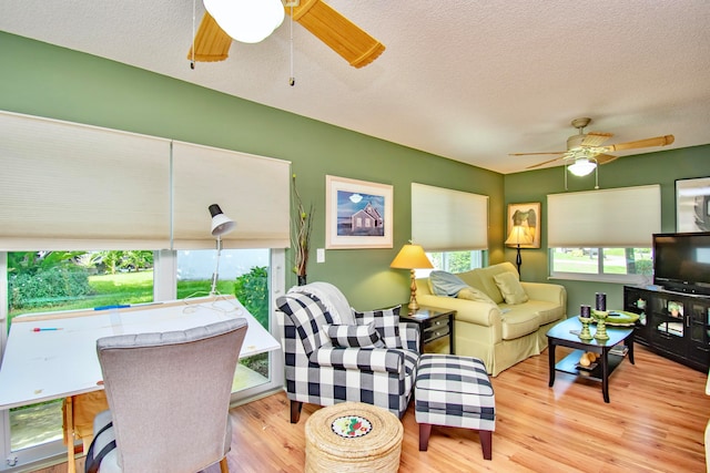 living room with ceiling fan, a textured ceiling, and light hardwood / wood-style flooring