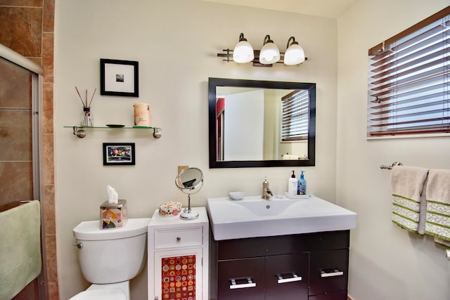 bathroom with a wealth of natural light, vanity, a shower with shower door, and toilet