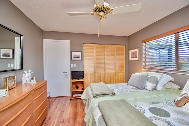 bedroom featuring light hardwood / wood-style flooring, a textured ceiling, a closet, and ceiling fan