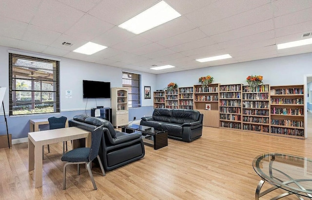 living room with light hardwood / wood-style floors and a drop ceiling