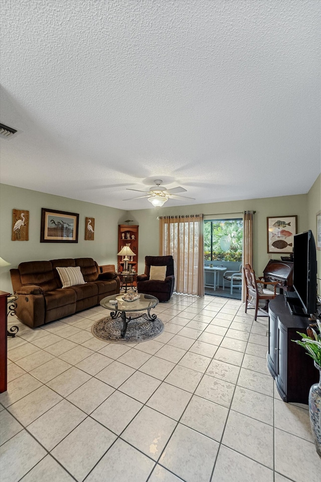 living room featuring ceiling fan, a textured ceiling, and light tile patterned floors