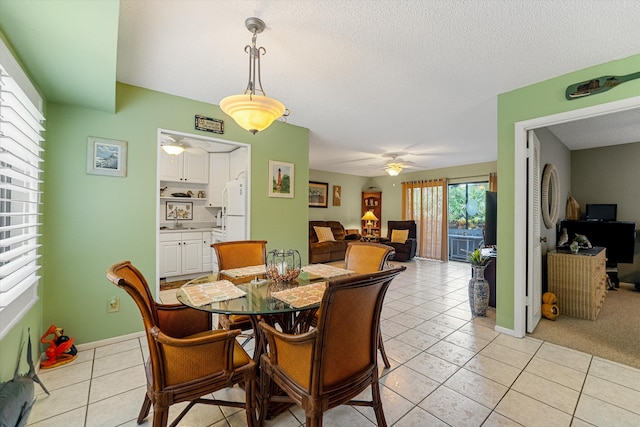 dining space with a textured ceiling, light tile patterned flooring, sink, and ceiling fan