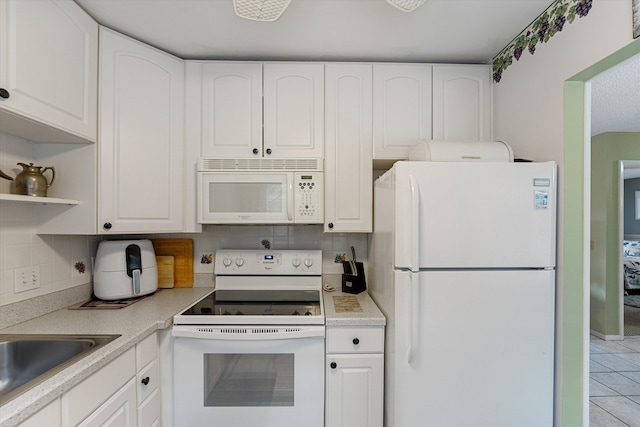 kitchen featuring white appliances, tasteful backsplash, white cabinetry, and light tile patterned flooring