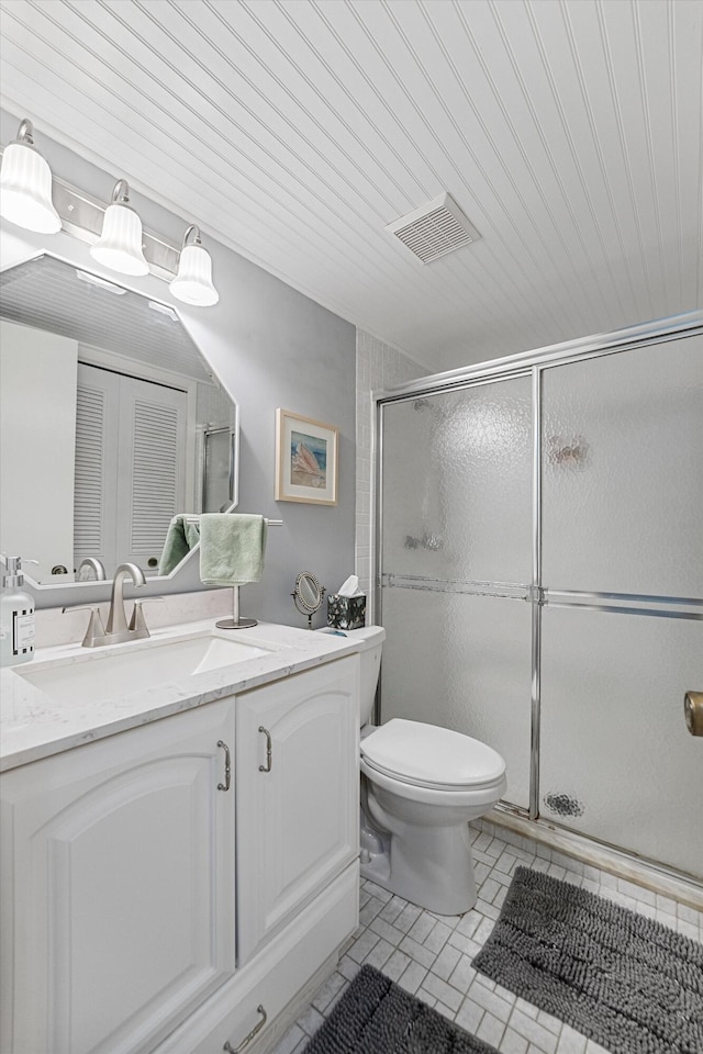 bathroom featuring vanity, toilet, tile patterned floors, and a shower with door