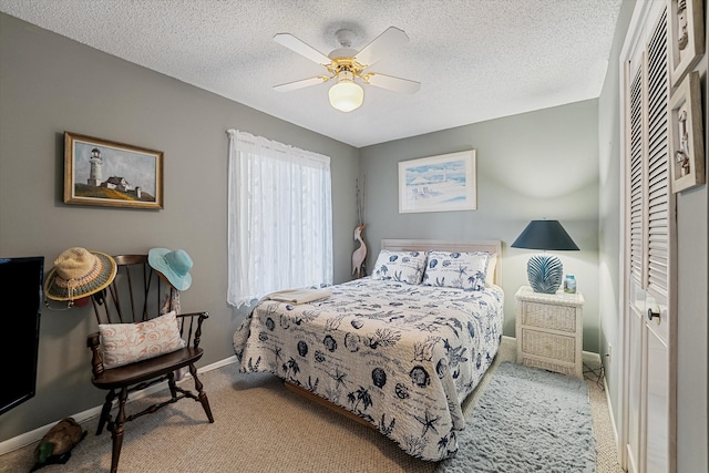 bedroom with a closet, ceiling fan, a textured ceiling, and light colored carpet