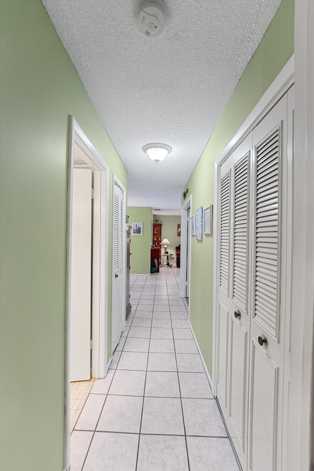 hallway featuring a textured ceiling and light tile patterned floors