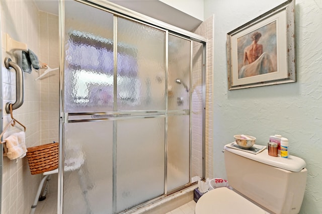 bathroom featuring tile patterned floors, toilet, and a shower with door