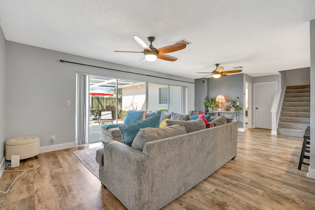 living room featuring light wood-type flooring, a textured ceiling, and ceiling fan