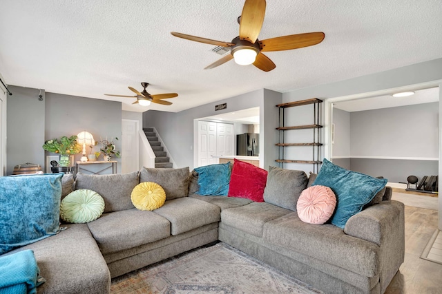 living room featuring a textured ceiling, light wood-type flooring, and ceiling fan