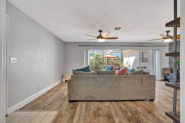 living room featuring ceiling fan, a textured ceiling, and light wood-type flooring