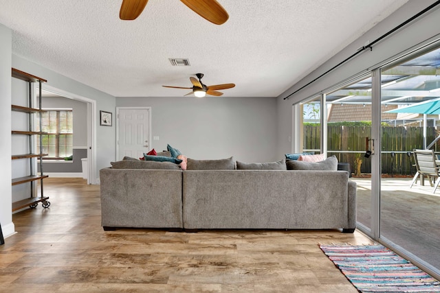 living room with ceiling fan, wood-type flooring, and a textured ceiling