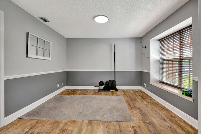 spare room with light hardwood / wood-style floors and a textured ceiling