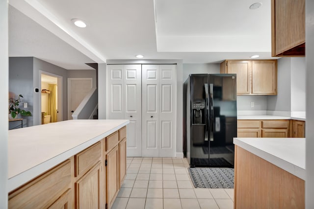 kitchen featuring black refrigerator with ice dispenser, light tile patterned floors, and light brown cabinetry