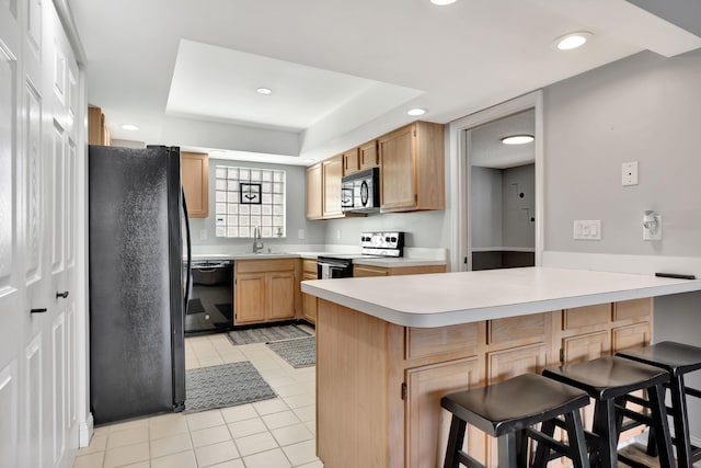 kitchen featuring kitchen peninsula, black appliances, sink, light tile patterned flooring, and a breakfast bar