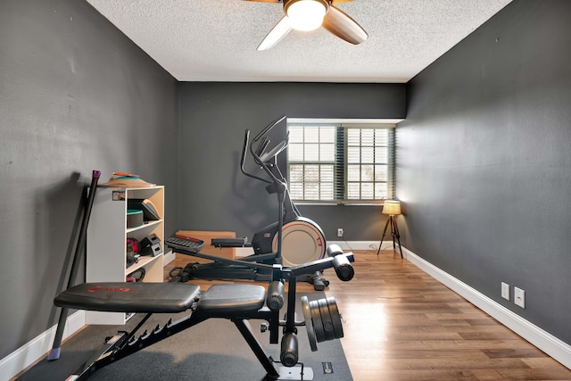 exercise room featuring wood-type flooring, ceiling fan, and a textured ceiling