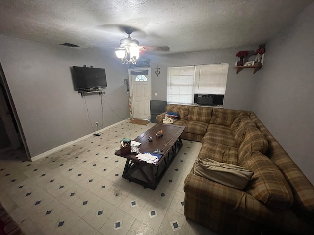 living room with cooling unit, a textured ceiling, and ceiling fan