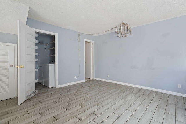 unfurnished bedroom featuring a closet, light hardwood / wood-style flooring, a textured ceiling, washer / dryer, and a chandelier