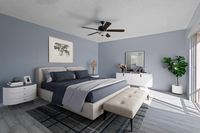 bedroom with ceiling fan, light hardwood / wood-style flooring, and a textured ceiling