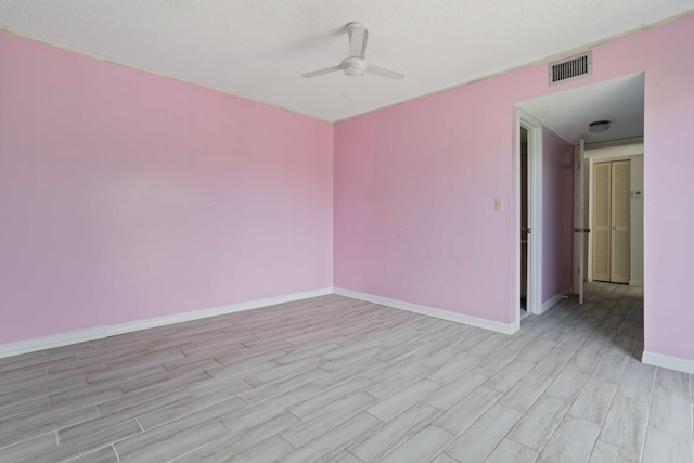 spare room featuring ceiling fan, light wood-type flooring, and a textured ceiling