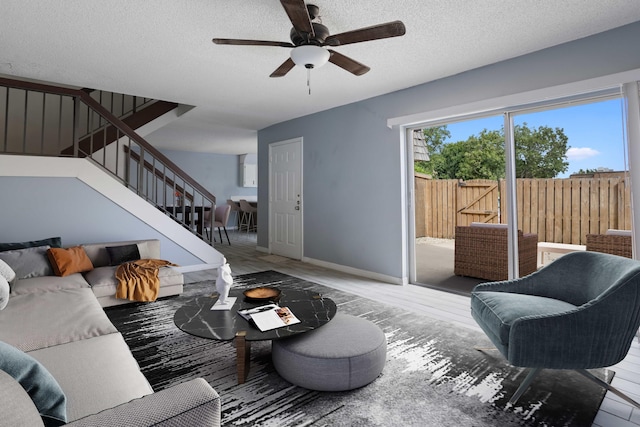 living room featuring hardwood / wood-style floors, ceiling fan, and a textured ceiling