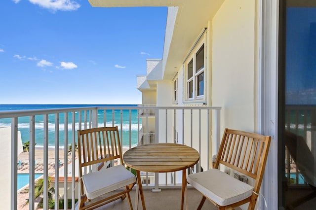 balcony with a water view and a view of the beach