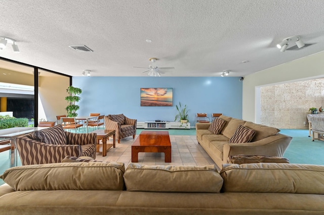 living room featuring a textured ceiling, rail lighting, light tile patterned floors, and ceiling fan