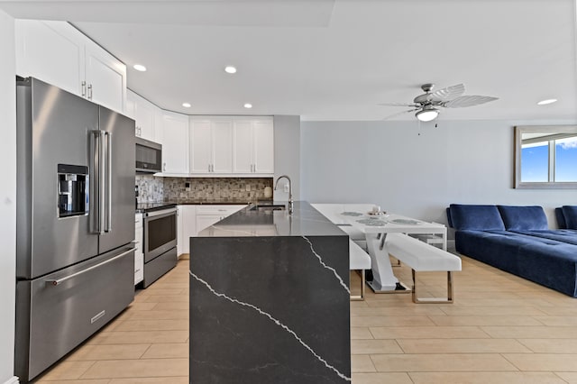 kitchen featuring light wood-type flooring, backsplash, ceiling fan, stainless steel appliances, and white cabinets